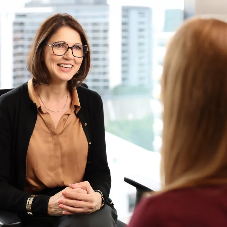 Annelie Peusschers in glasses, smiling, in a bright city office